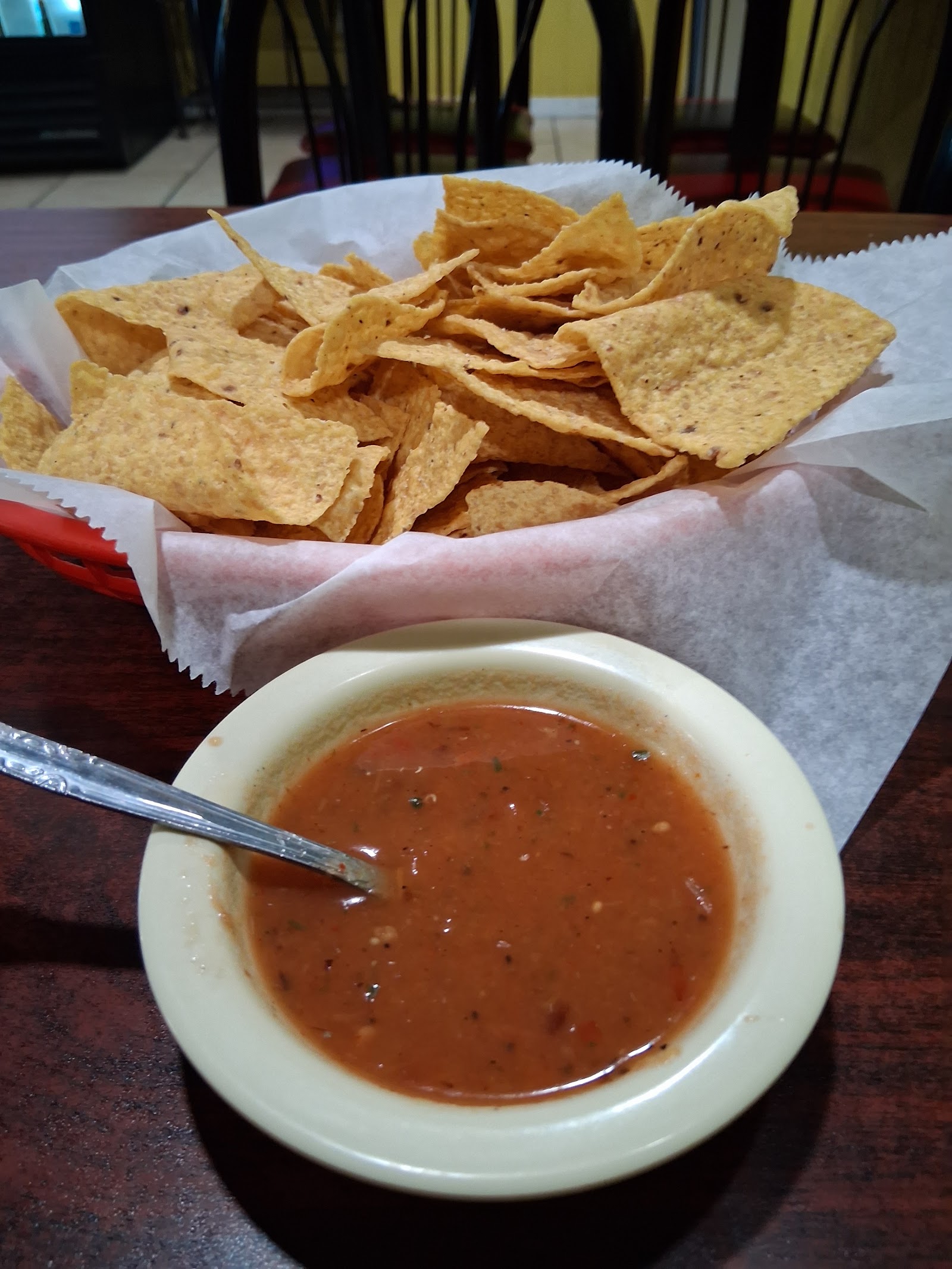 Basket of tortilla chips with a bowl of house-made red salsa
